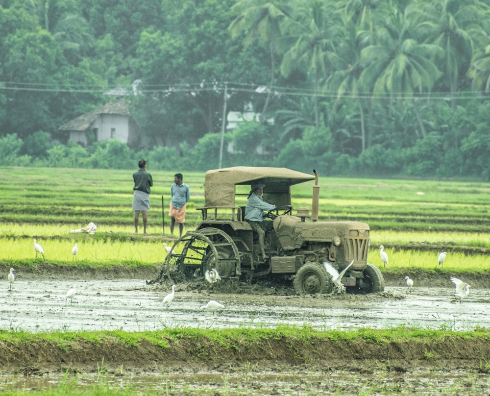 people riding on green tractor on green grass field during daytime