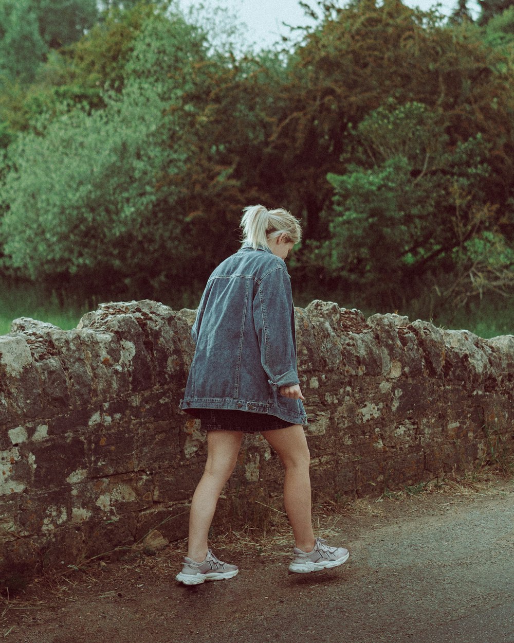 woman in blue long sleeve dress standing on gray concrete pathway during daytime