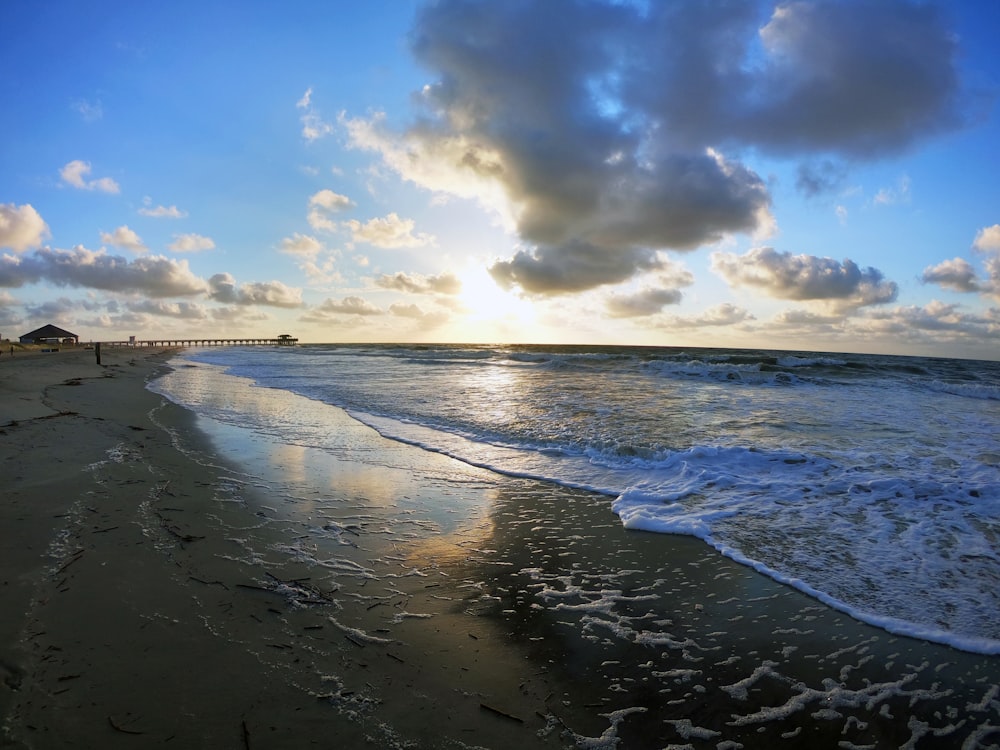 sea waves crashing on shore under blue and white cloudy sky during daytime