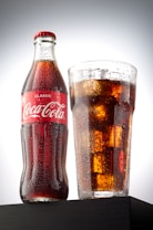 coca cola bottle beside drinking glass