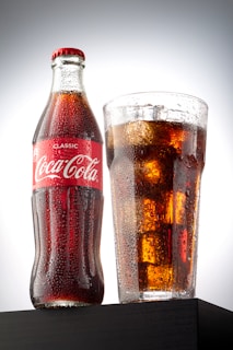 coca cola bottle beside drinking glass