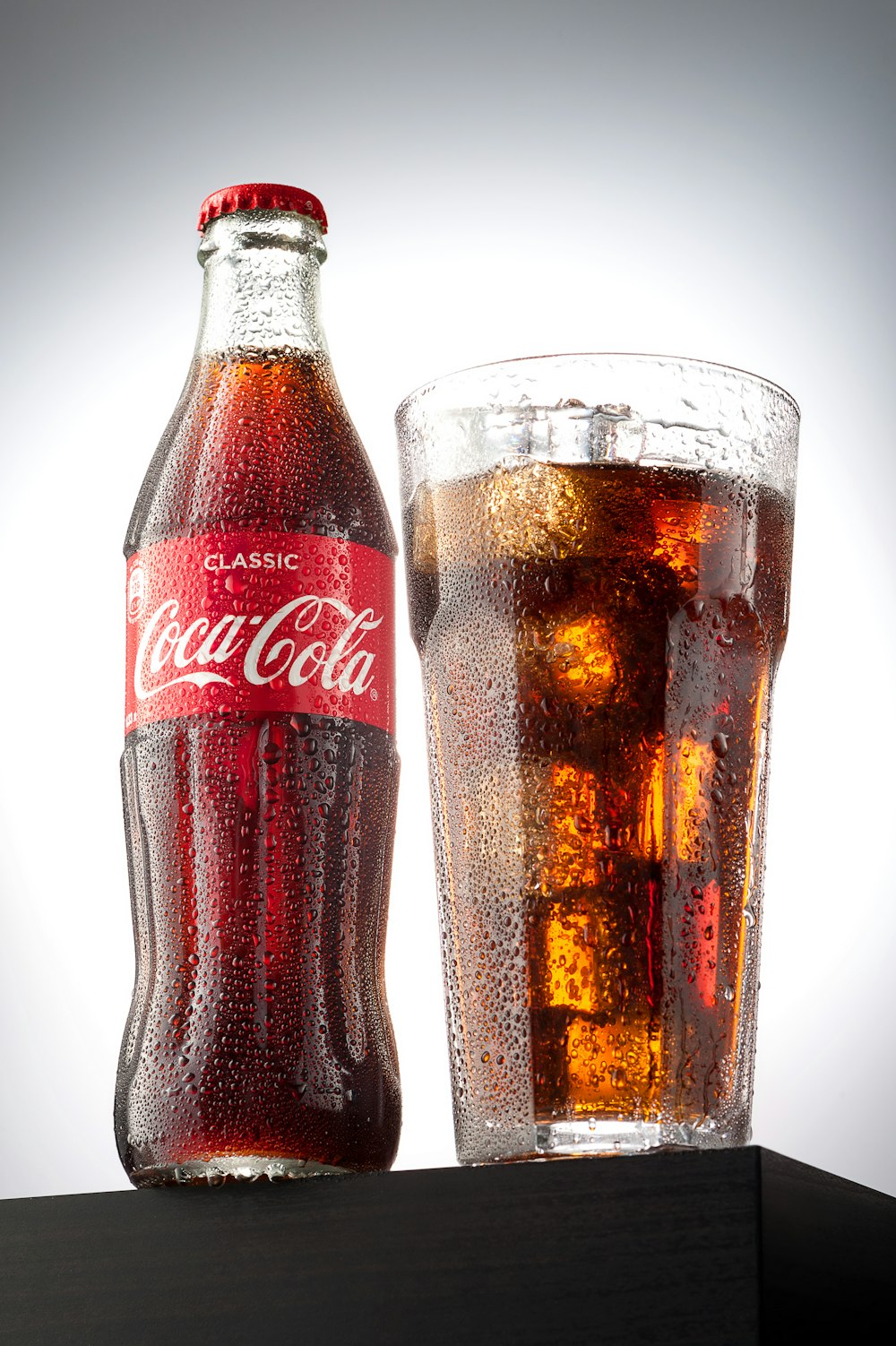 Botella de Coca Cola al lado de un vaso