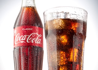 coca cola bottle beside drinking glass