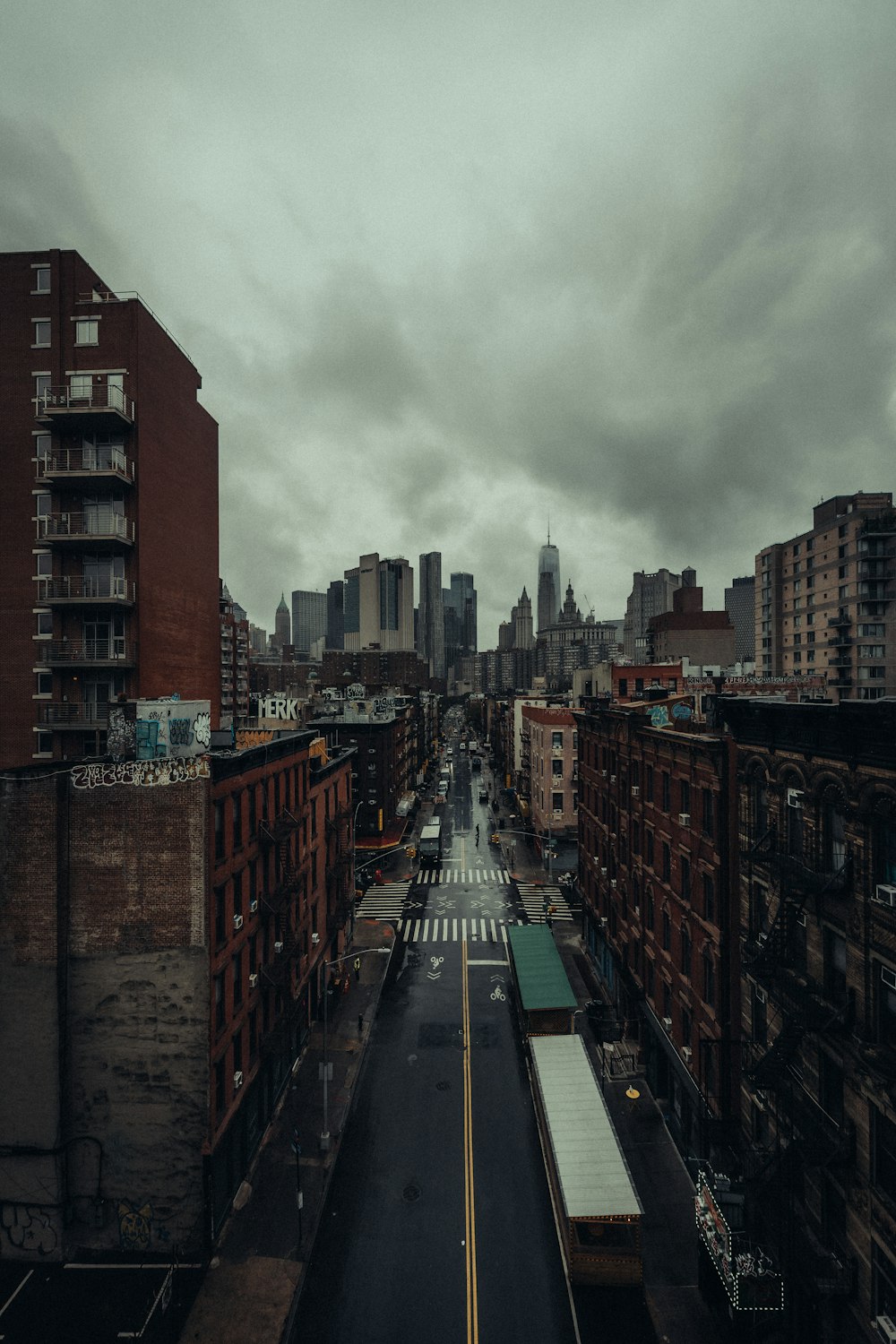 cars on road between high rise buildings under white clouds during daytime