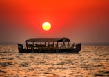 A traditional Sri Lankan boat floating on calm waters at sunset.