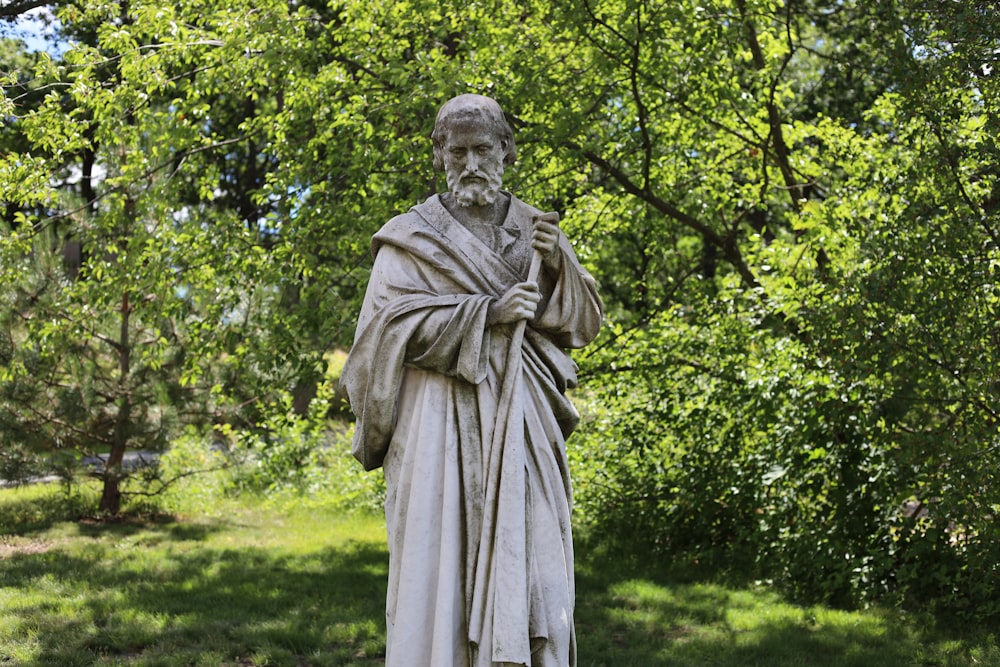 man statue near green trees during daytime