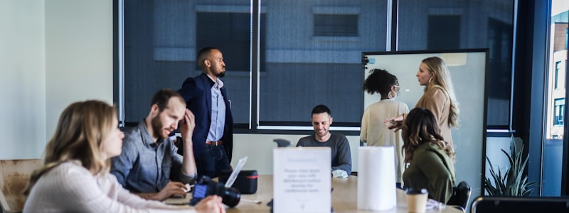 team collaborating busily in a meeting space, with various work modes and focus/stress levels evident