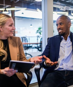 man in black suit jacket sitting beside woman in brown blazer