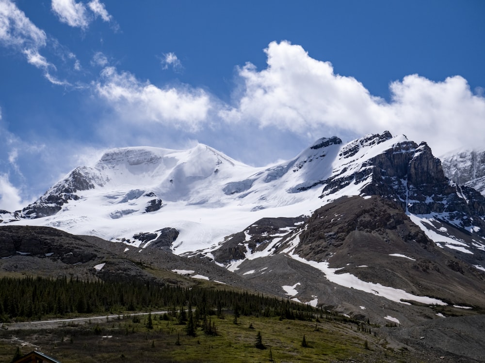 green trees and white snow covered mountain under blue sky and white clouds during daytime