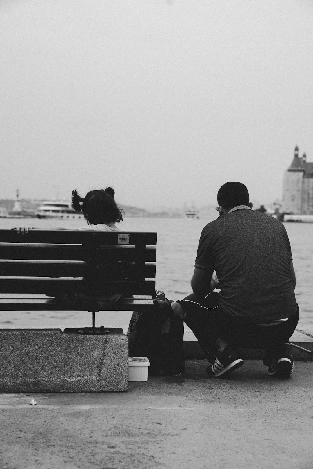 man and woman sitting on bench in grayscale photography