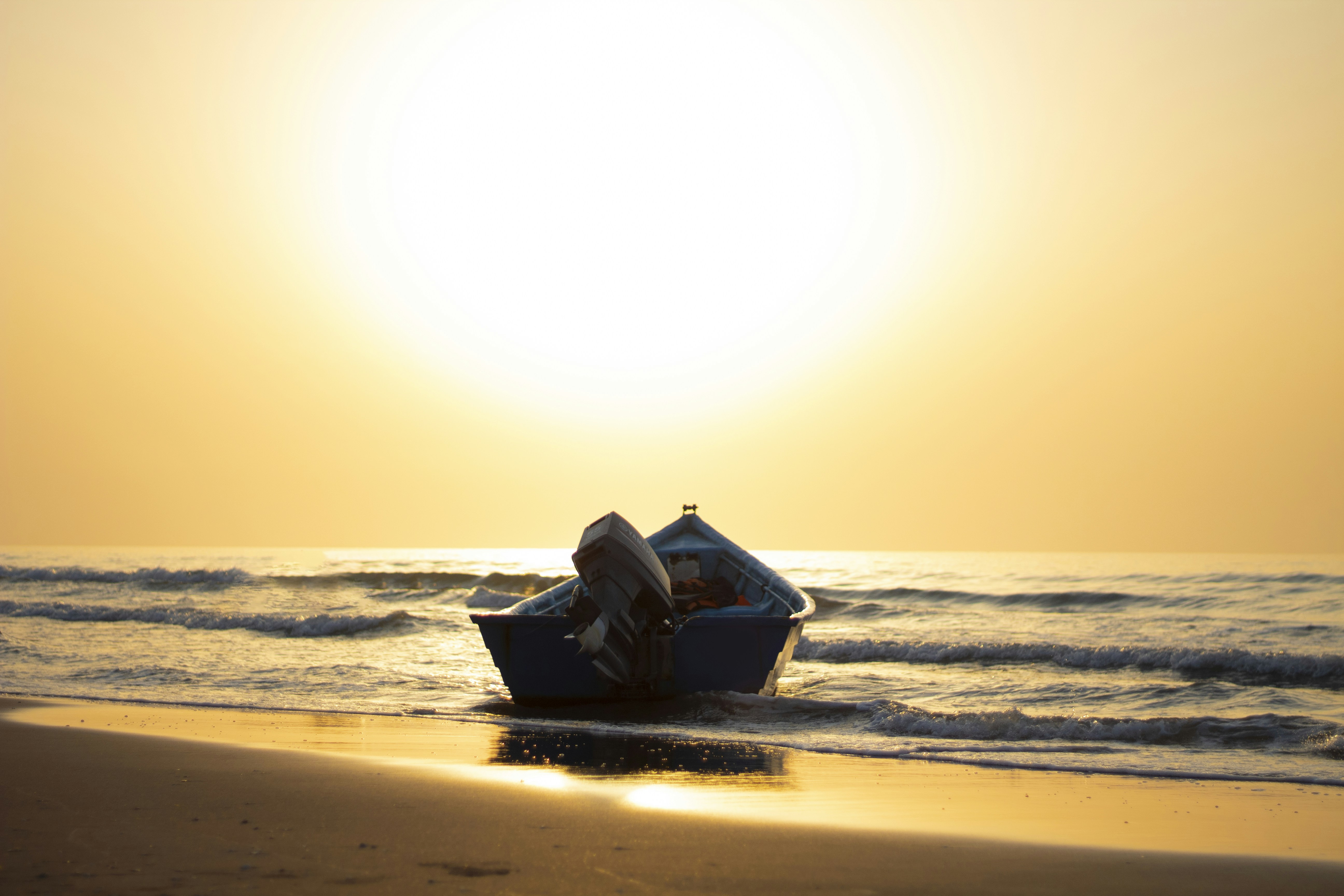 blue boat on sea shore during sunset
