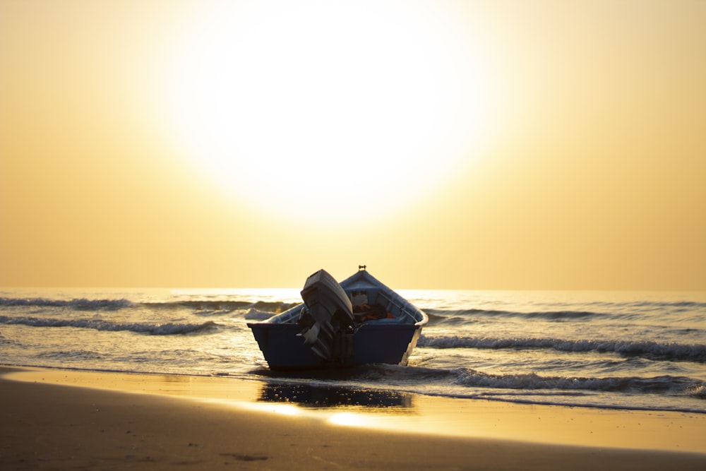 blue boat on sea shore during sunset