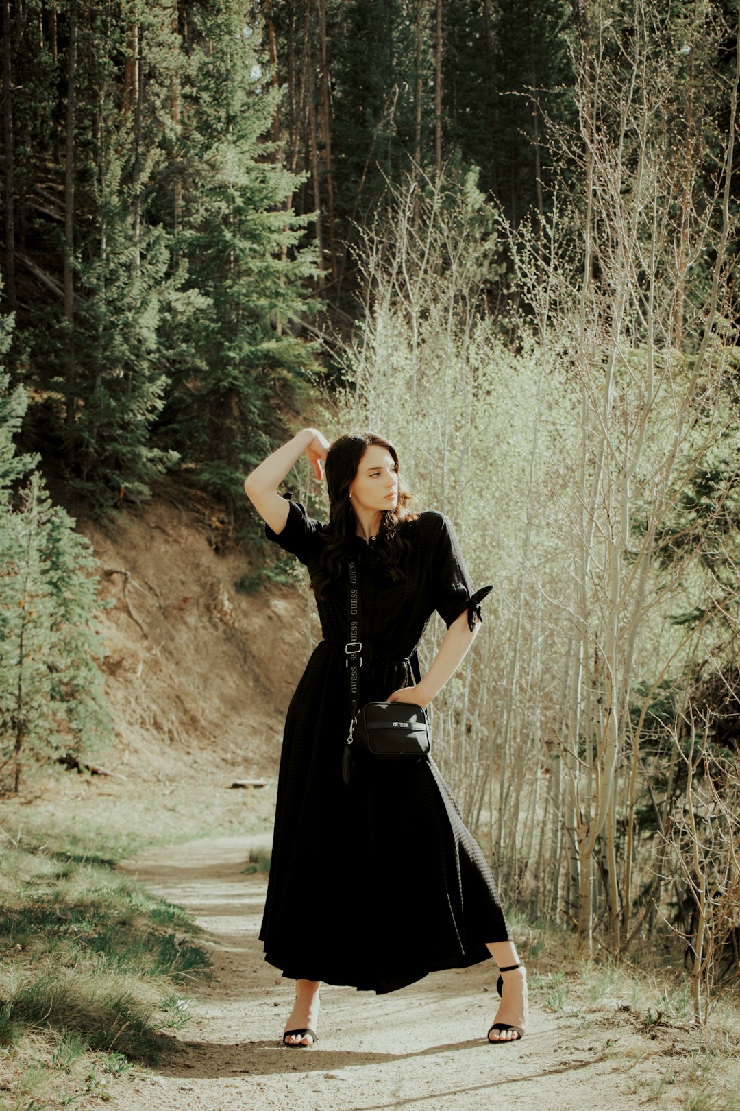 woman in black dress standing on dirt road