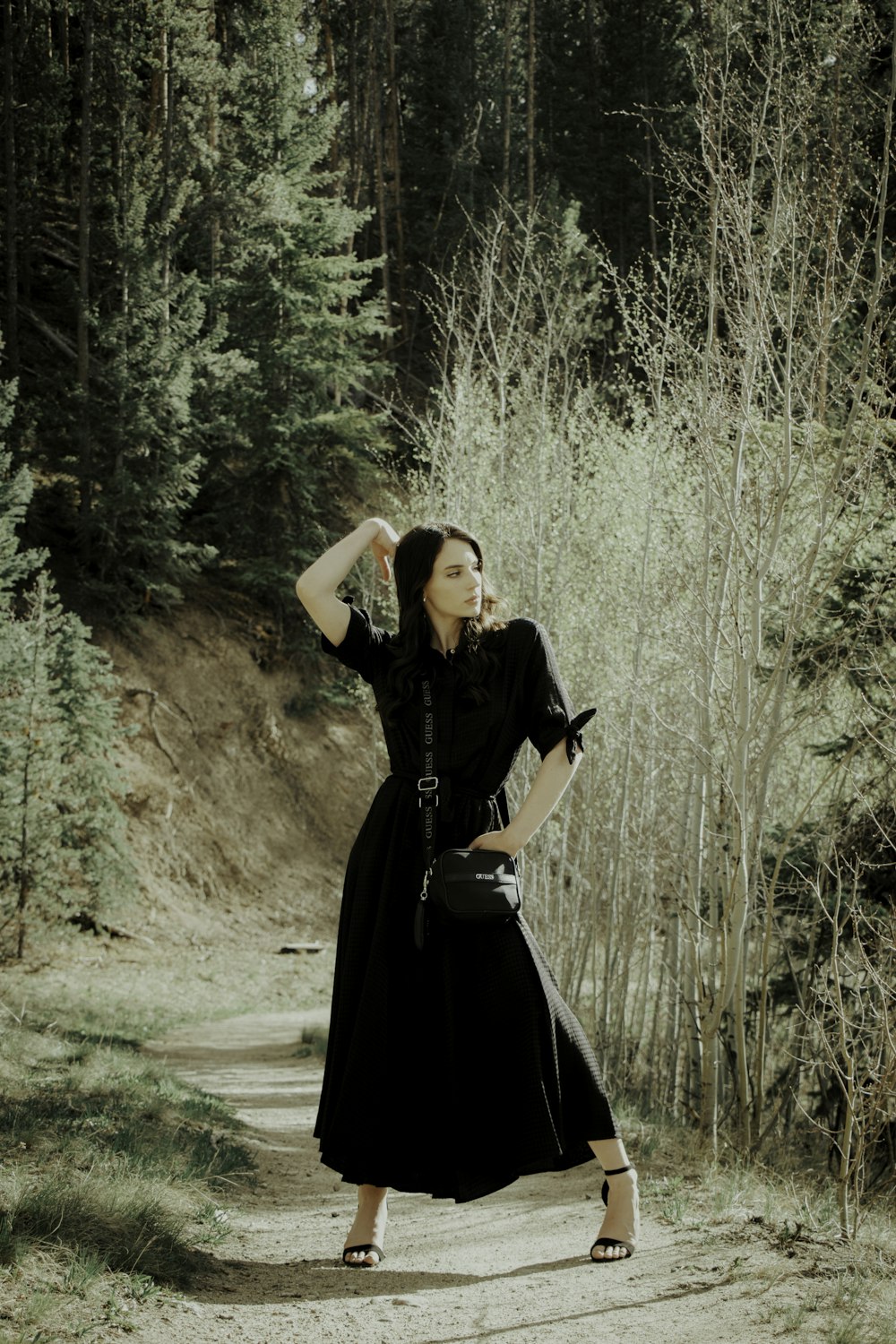 woman in black dress standing on dirt road