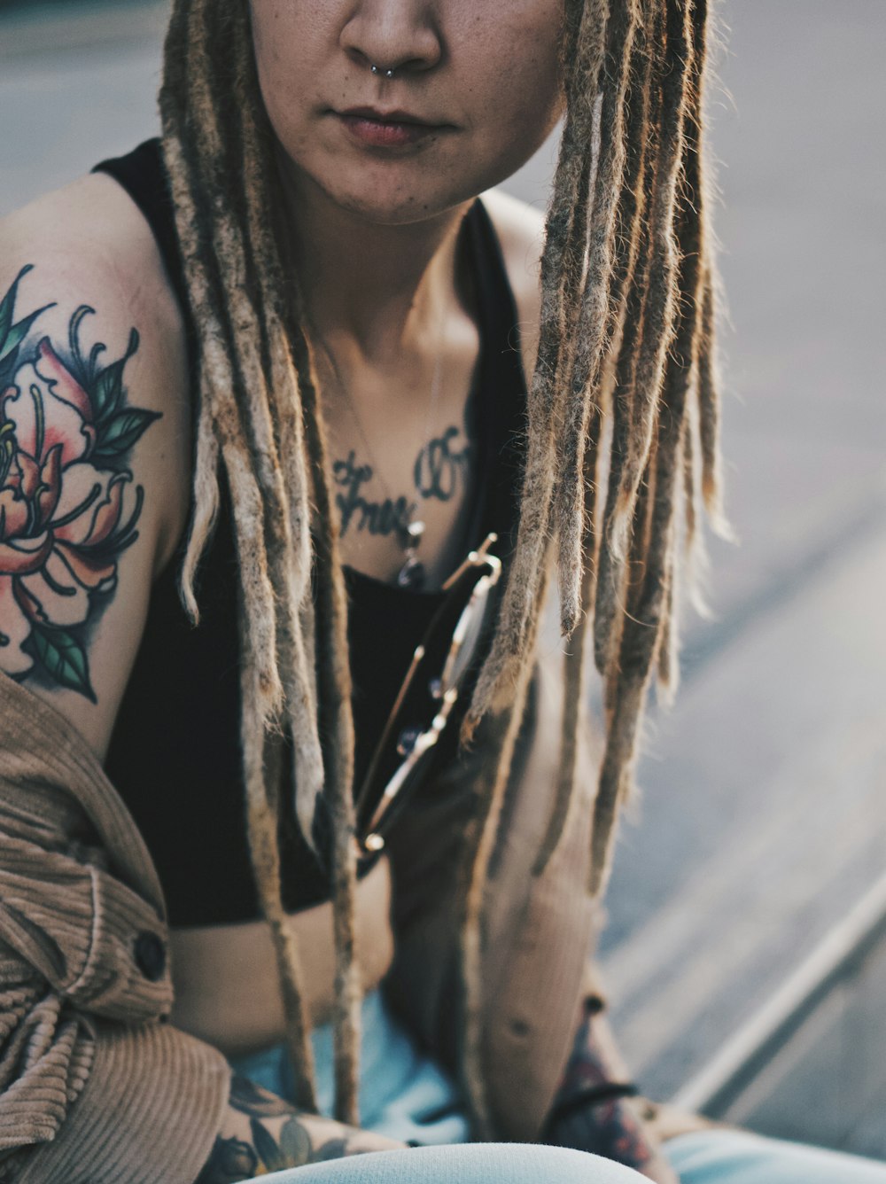 woman in black tank top with black and red floral tattoo on her right arm