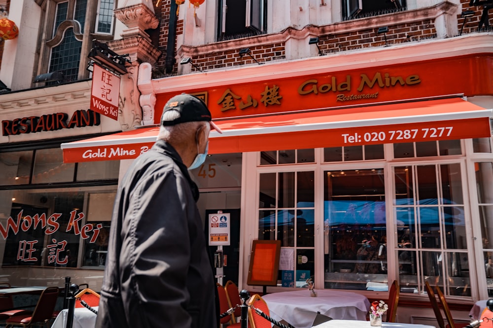 man in black and white jacket standing near store during daytime