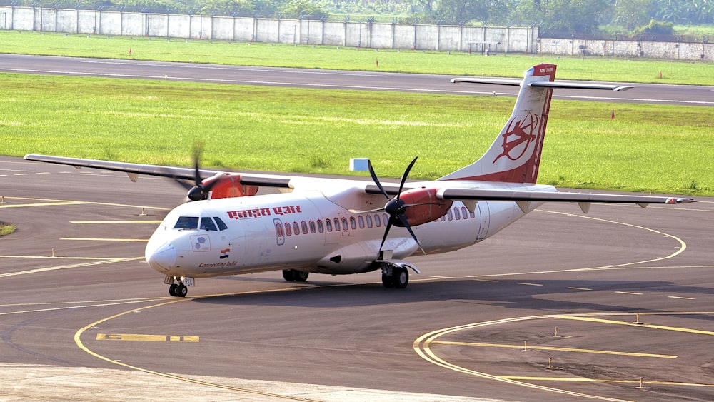 white and red passenger plane on airport during daytime