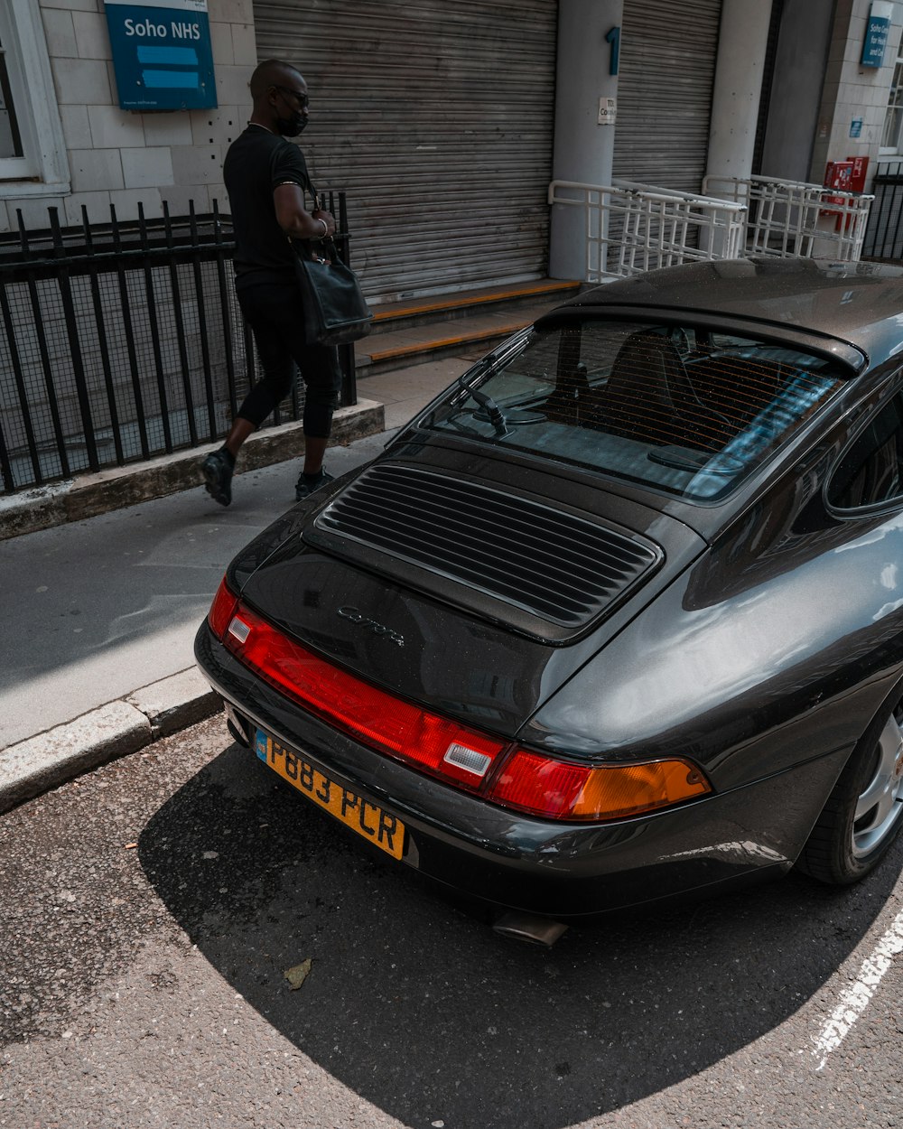 man in black jacket standing beside silver car