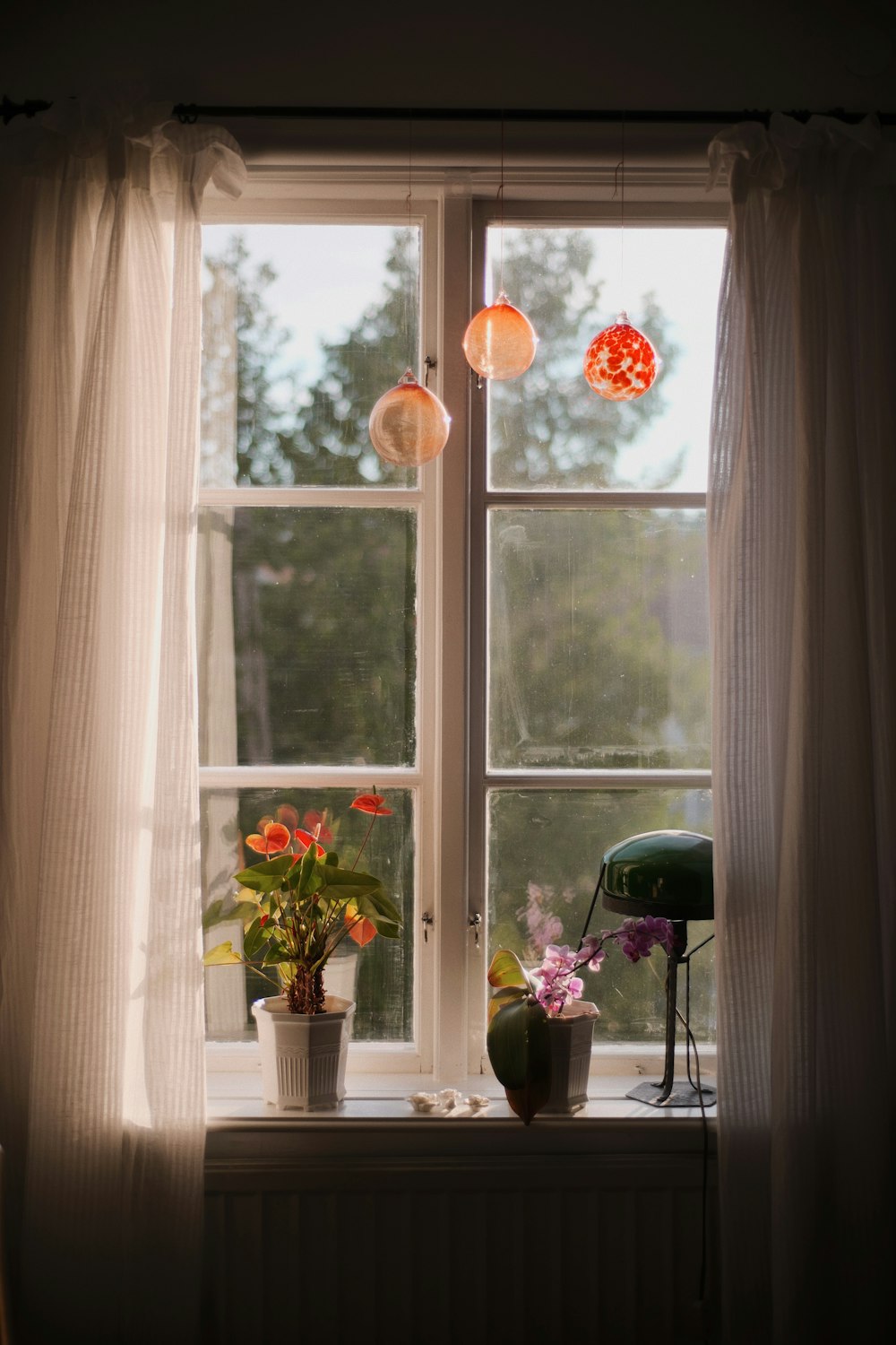 white and purple flowers in white ceramic vase beside window