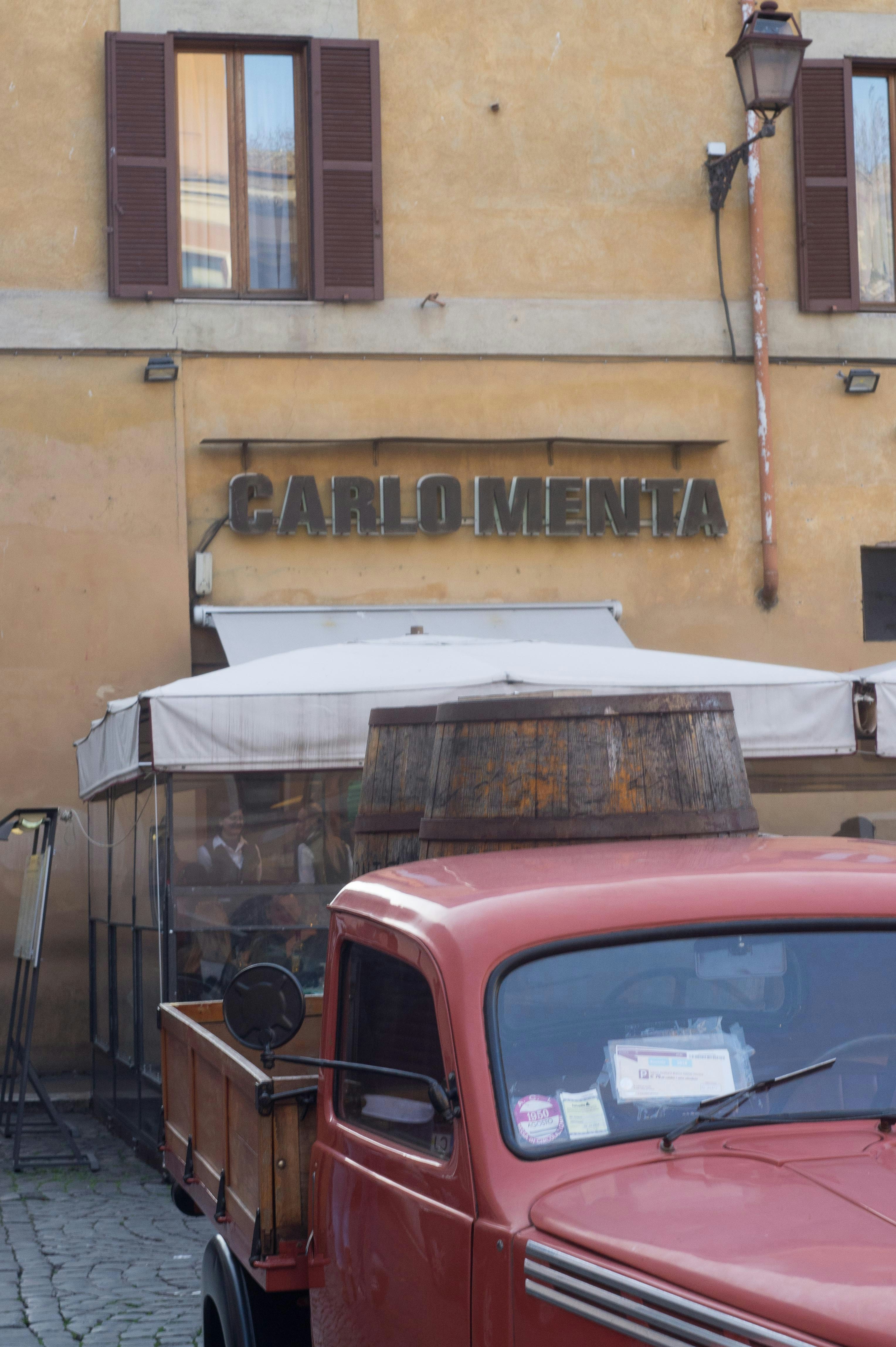 red car parked beside yellow concrete building during daytime