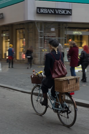 woman in red jacket riding on bicycle on street during daytime