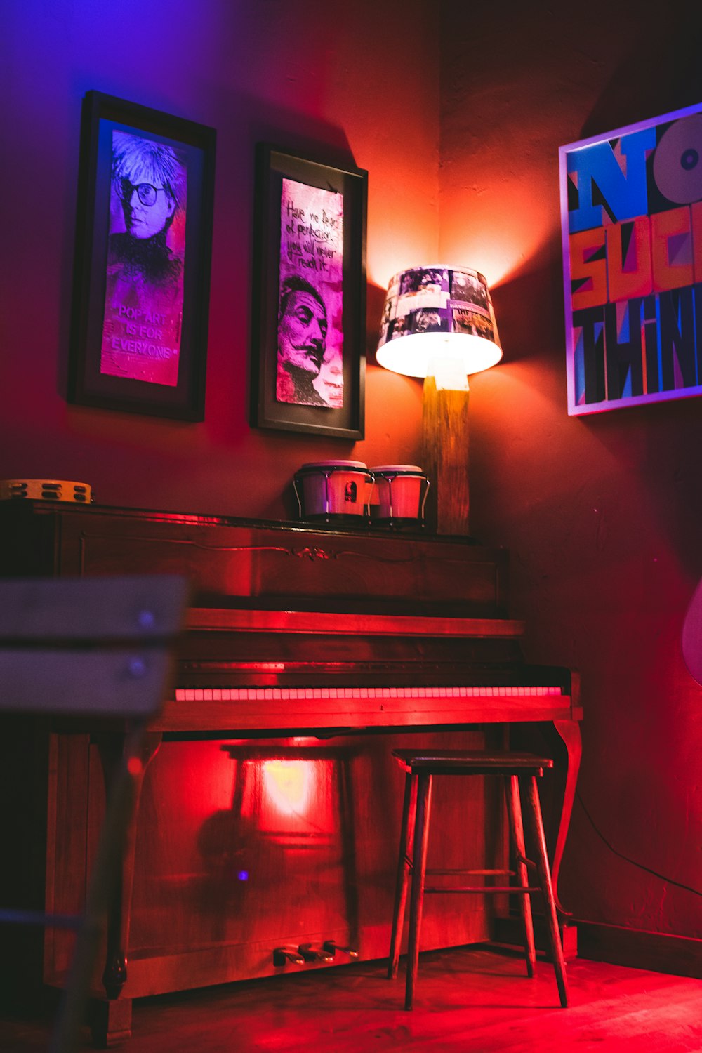 brown wooden upright piano beside red wall