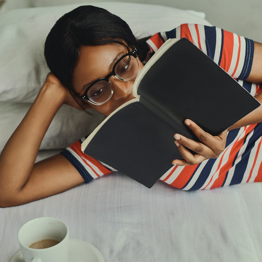 woman in white red and blue stripe tank top holding black tablet computer