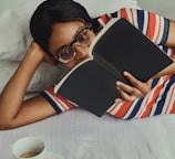 woman in white red and blue stripe tank top holding black tablet computer