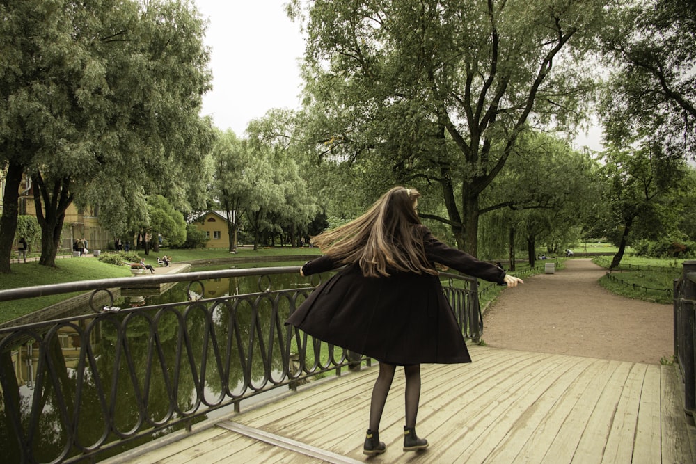 woman in black long sleeve dress standing on brown wooden floor during daytime