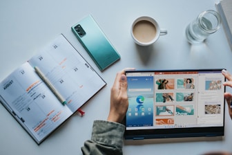 person using Windows 11 computer beside white ceramic mug on white table