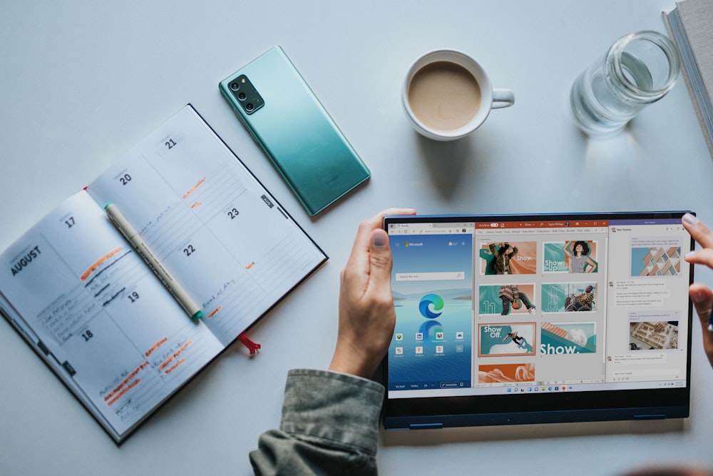 person using Windows 11 computer beside white ceramic mug on white table