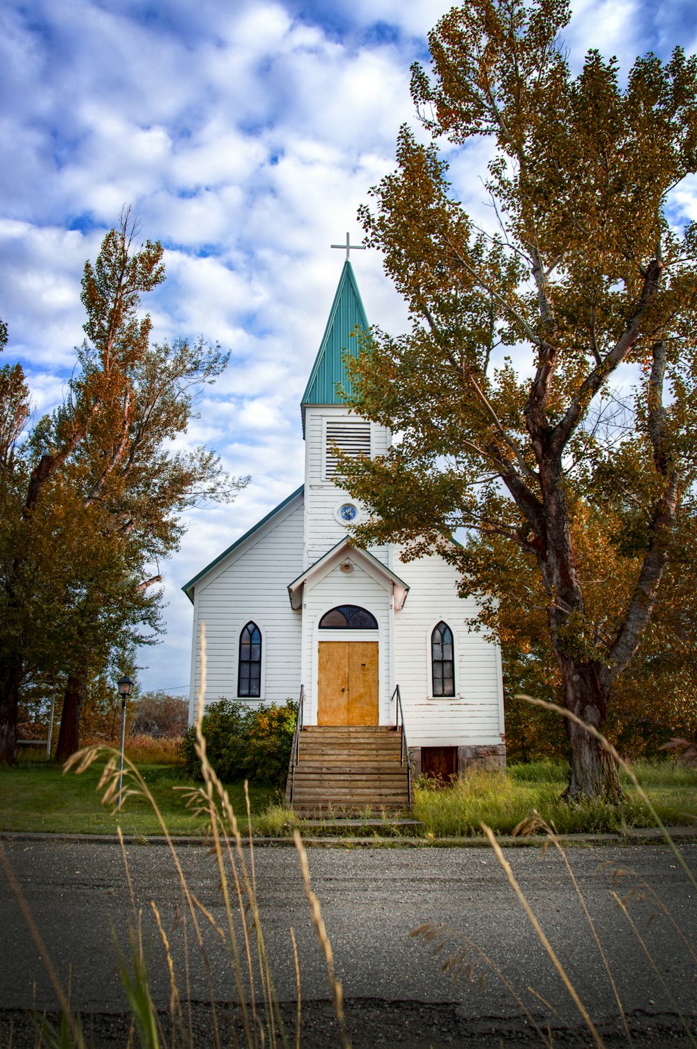 white and purple church near bare trees under blue sky during daytime