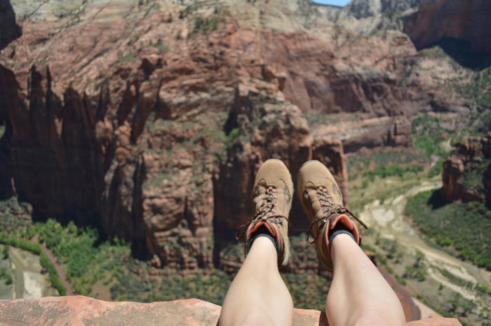 person in brown hiking shoes sitting on rock