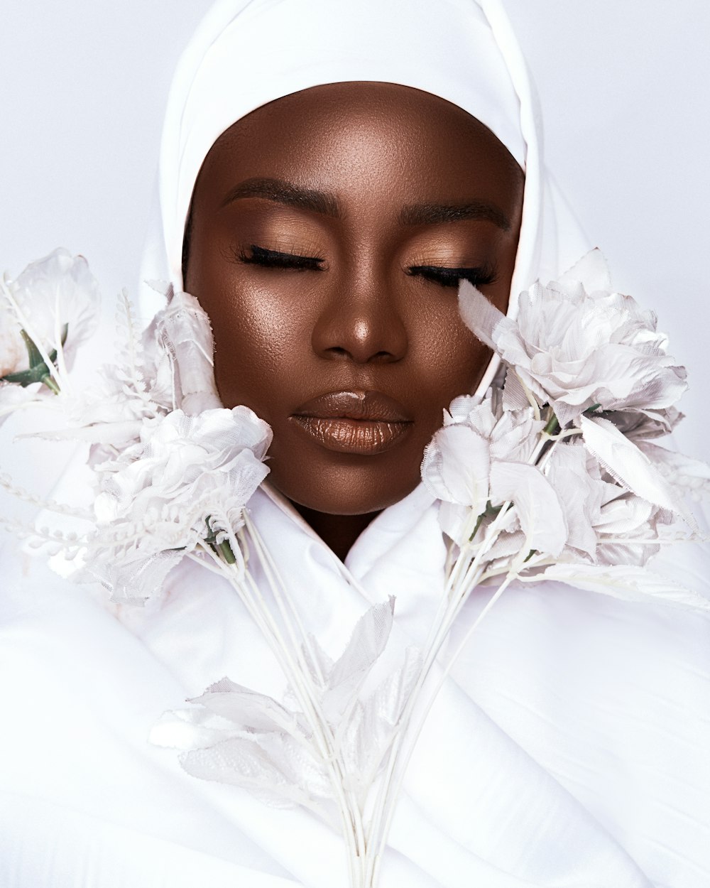 woman in white hijab holding white flowers