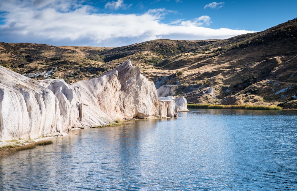 brown and green mountain beside body of water under blue sky during daytime