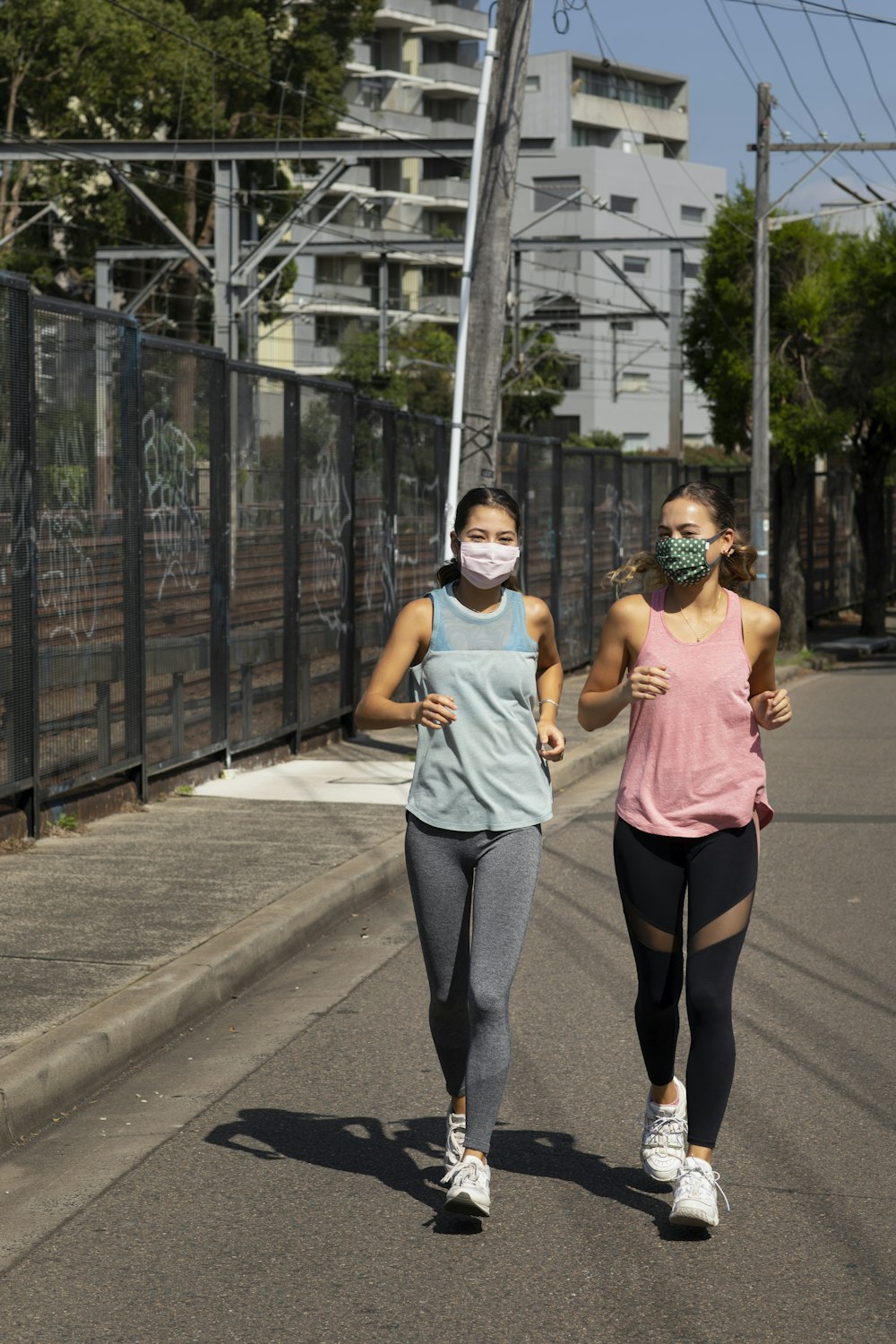 woman in pink tank top and gray pants standing on gray concrete road during daytime