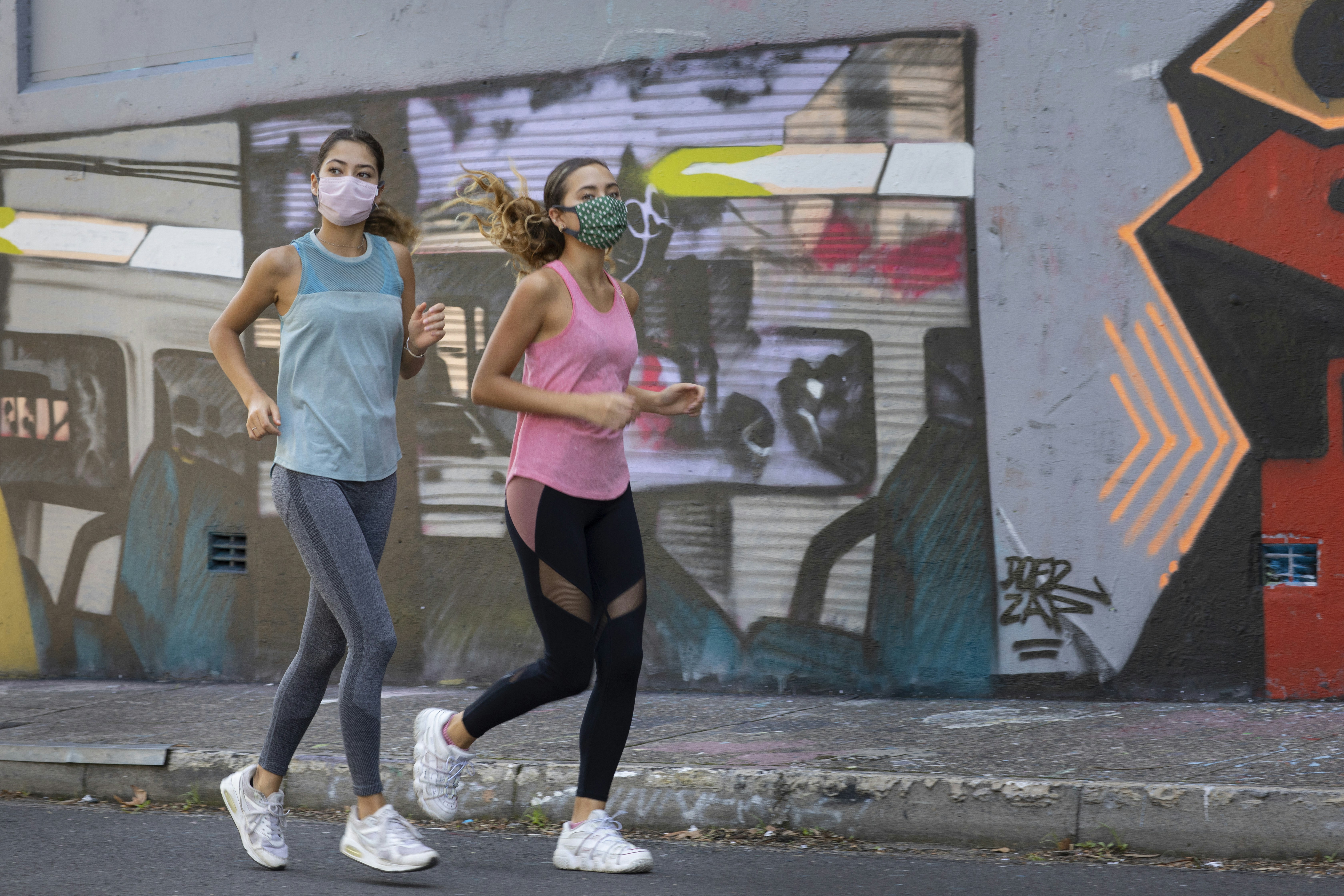 woman in pink sports bra and black leggings standing beside woman in white tank top and
