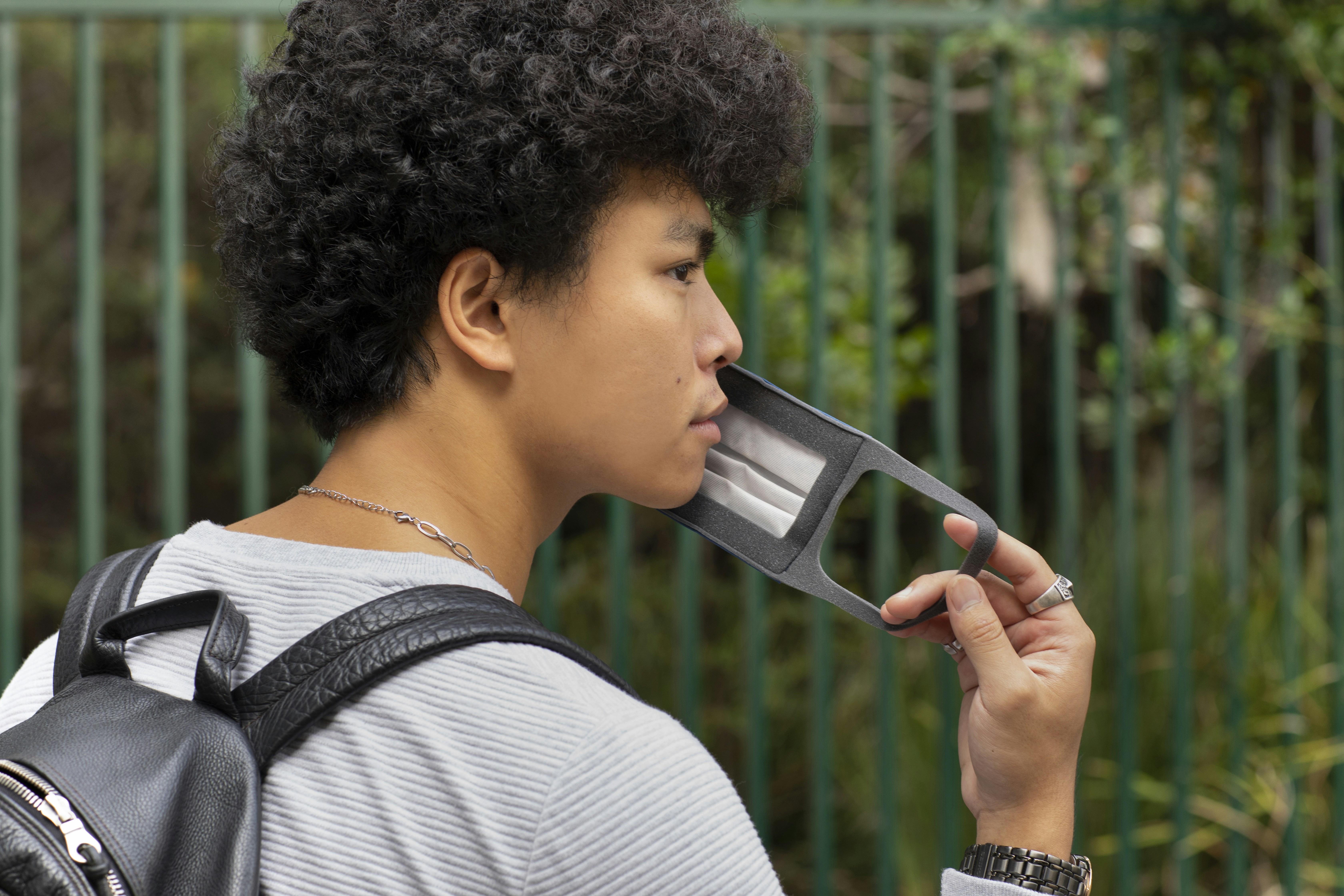 man in white and gray striped shirt holding gray smartphone