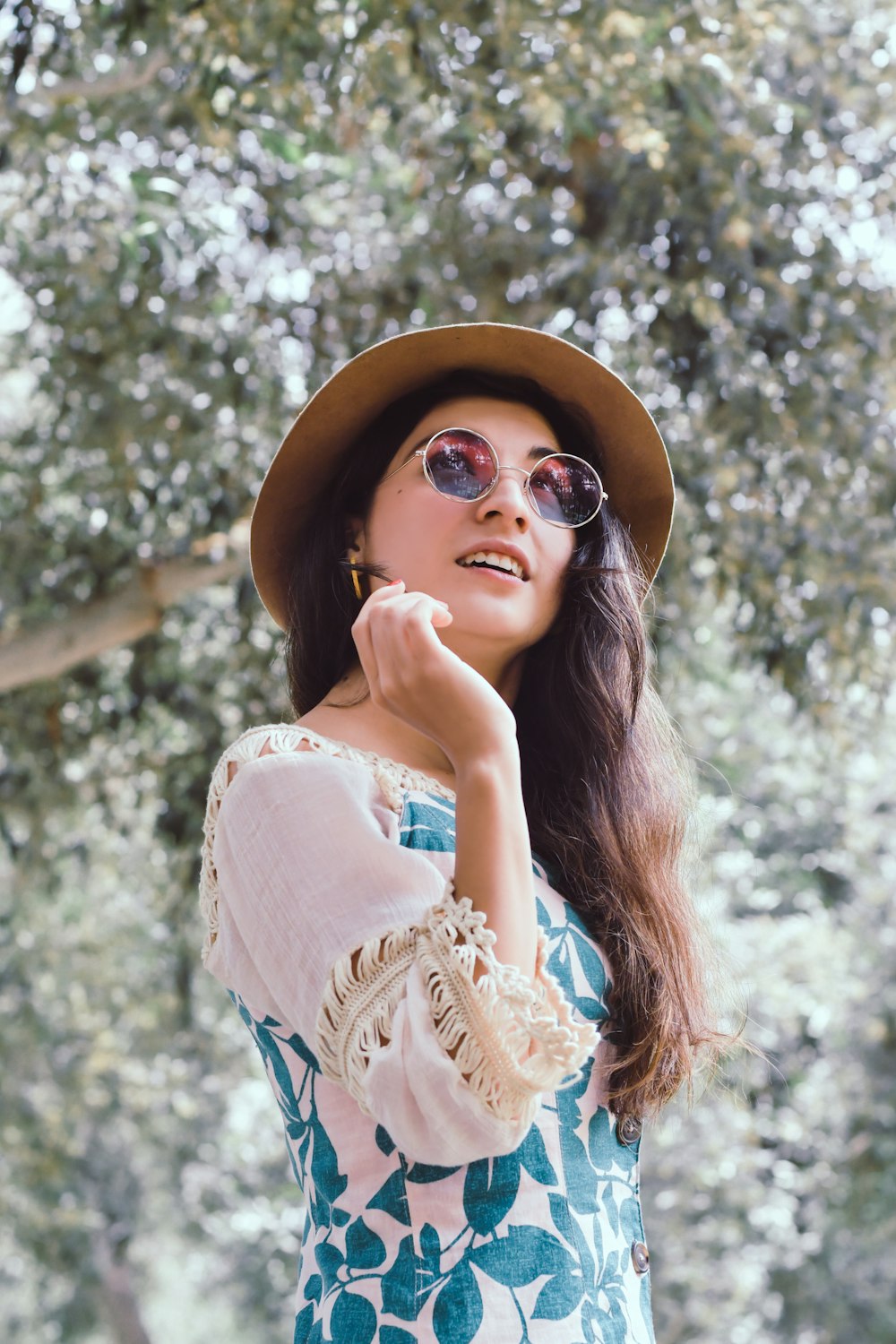 woman in blue and white floral sleeveless dress wearing brown sun hat