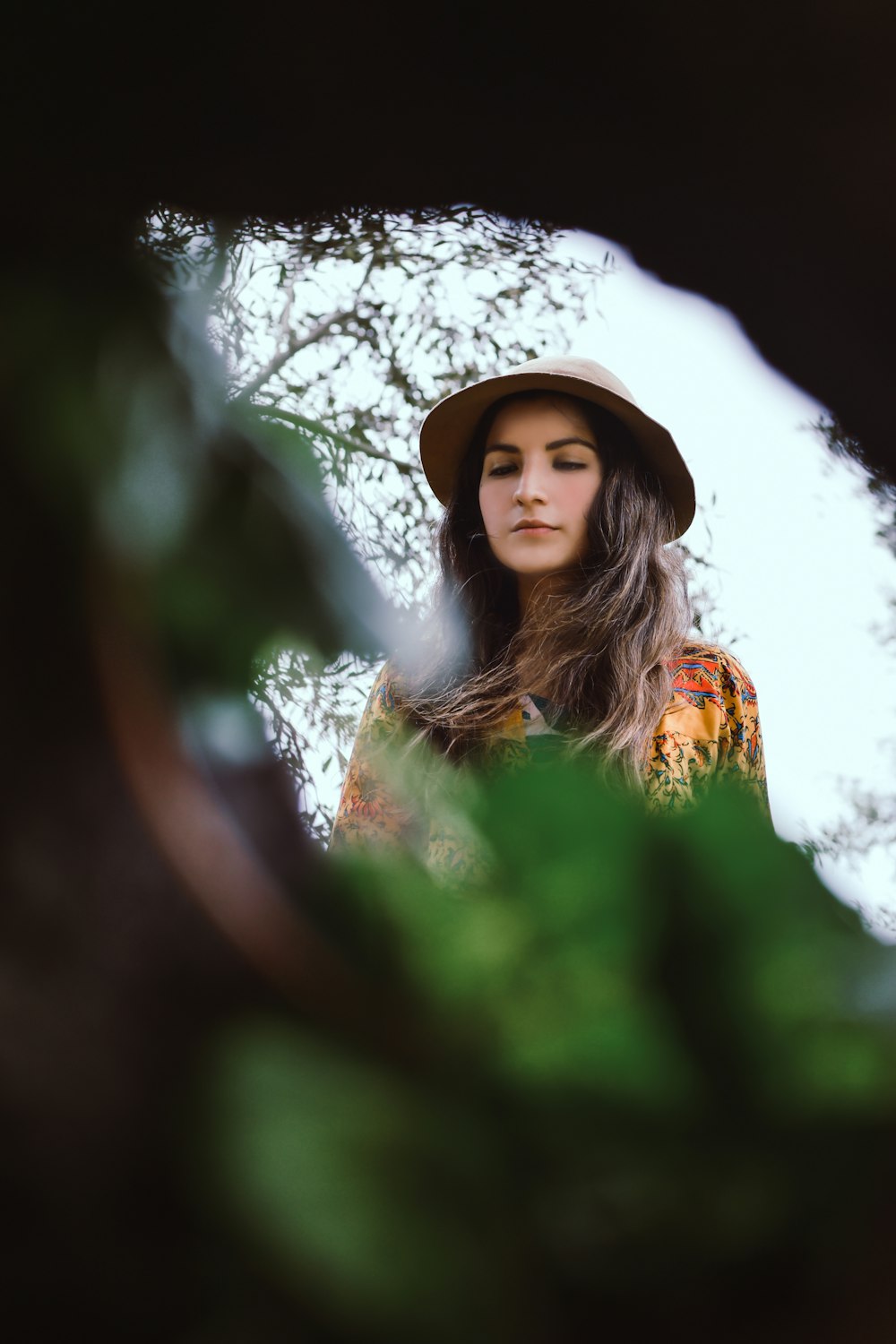 woman in yellow and white floral dress standing near tree during daytime