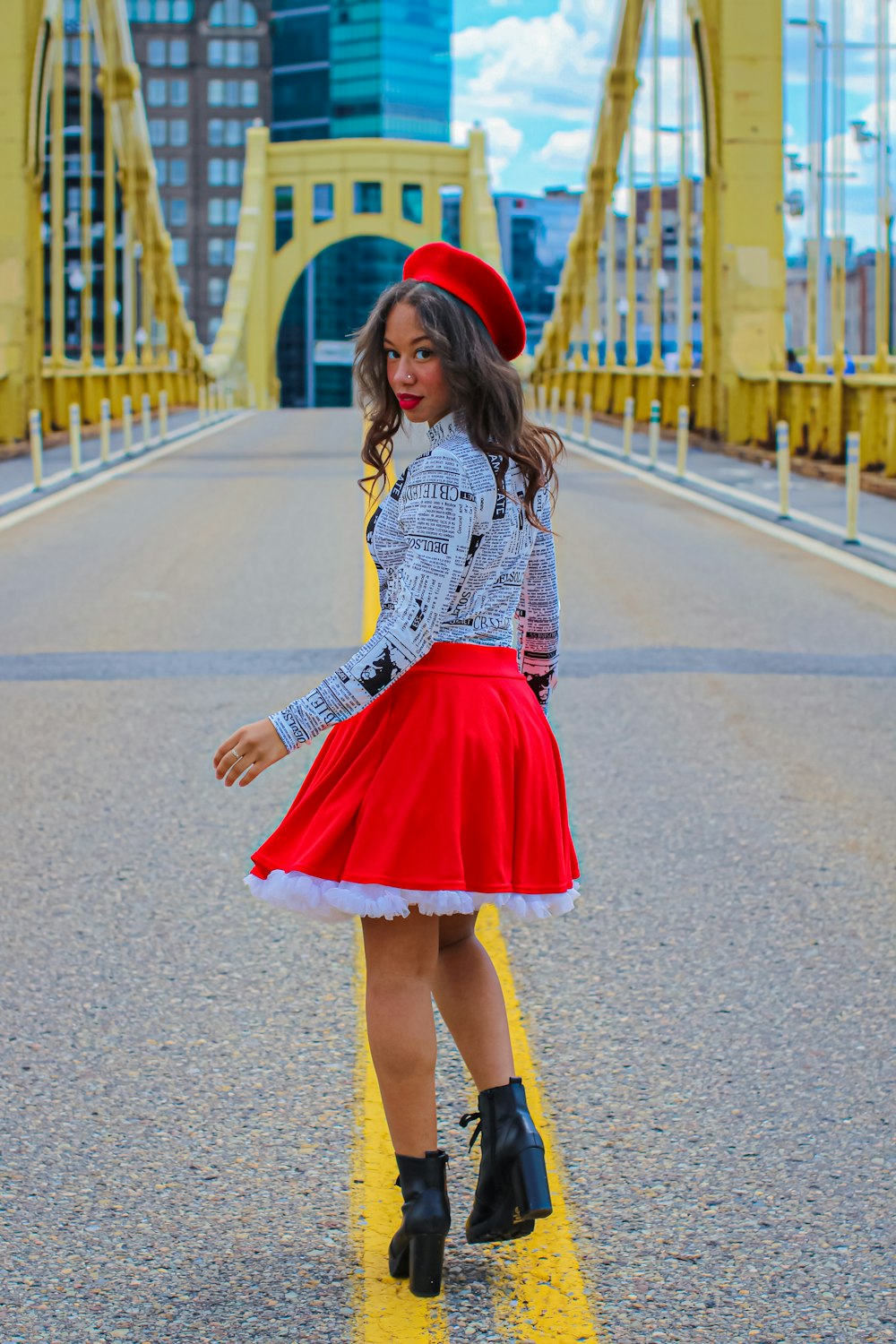woman in black and white long sleeve shirt and red skirt standing on gray asphalt road