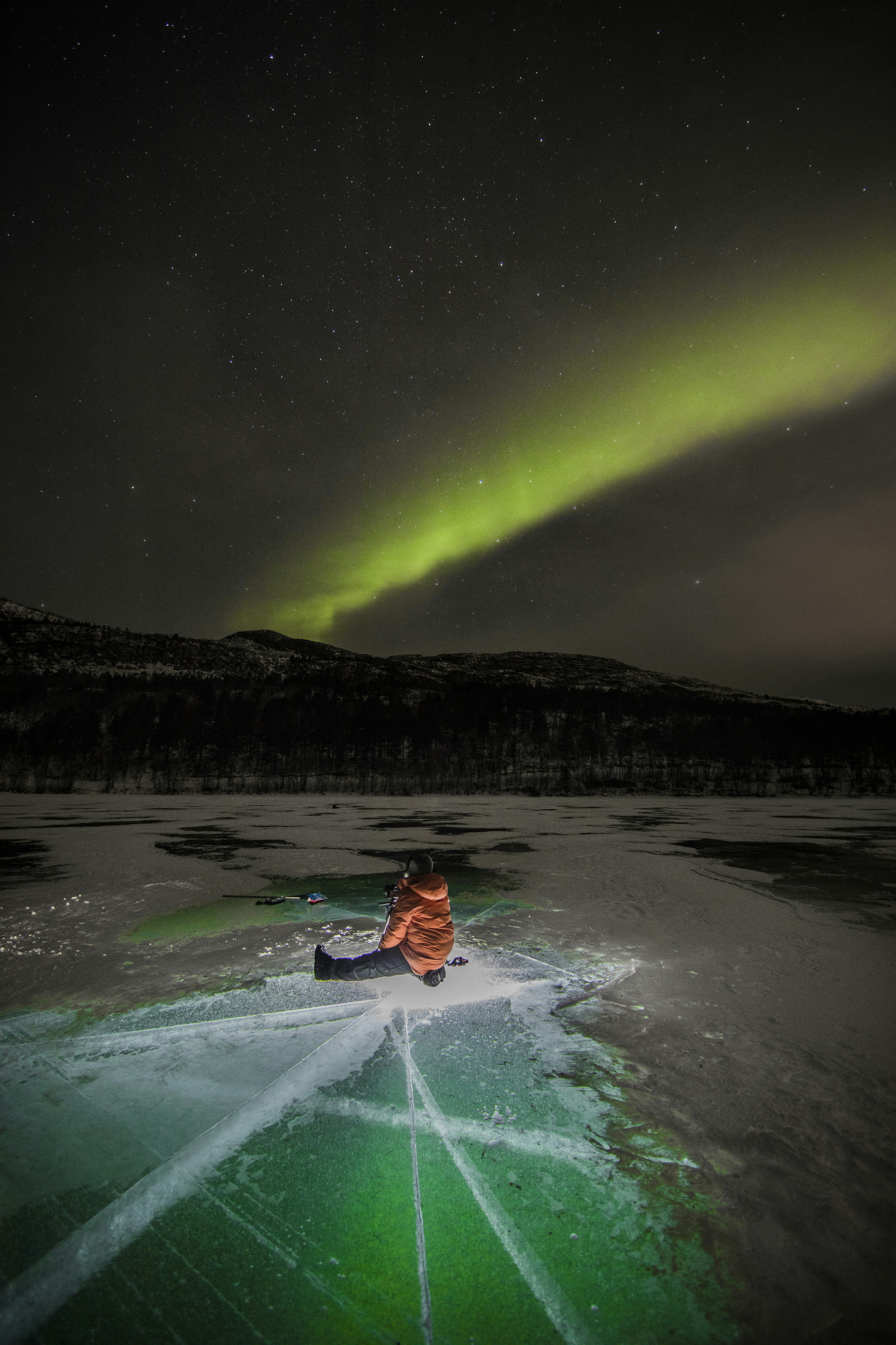 person in red hoodie sitting on green kayak on snow covered ground during night time