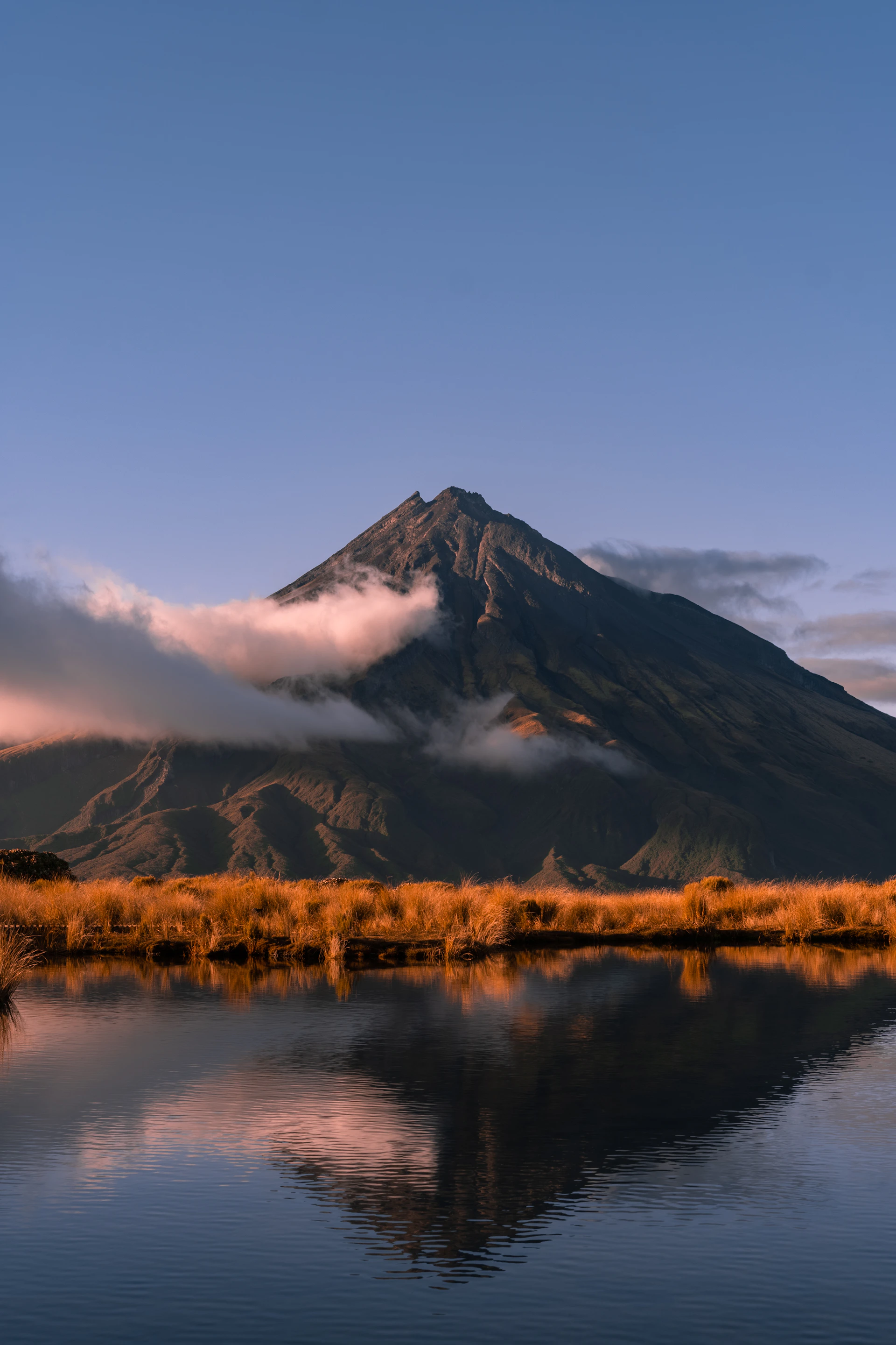 brown grass field near mountain under white clouds during daytime