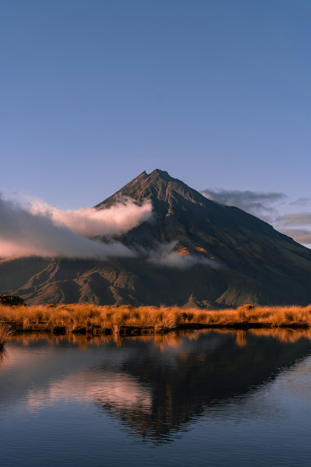 brown grass field near mountain under white clouds during daytime