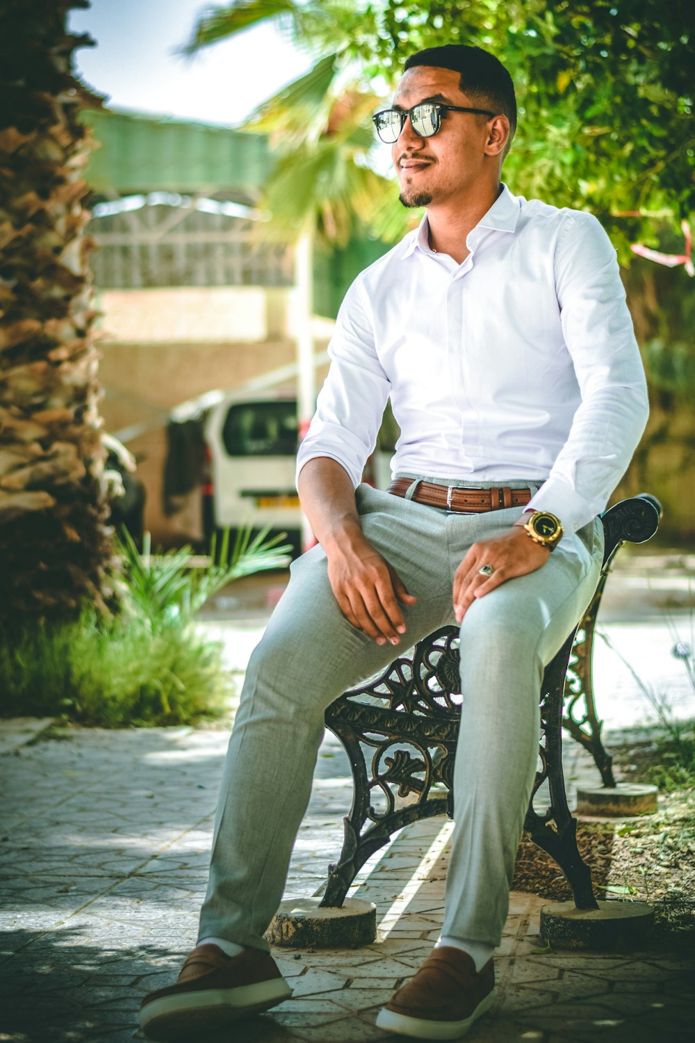 man in white dress shirt sitting on black metal bench