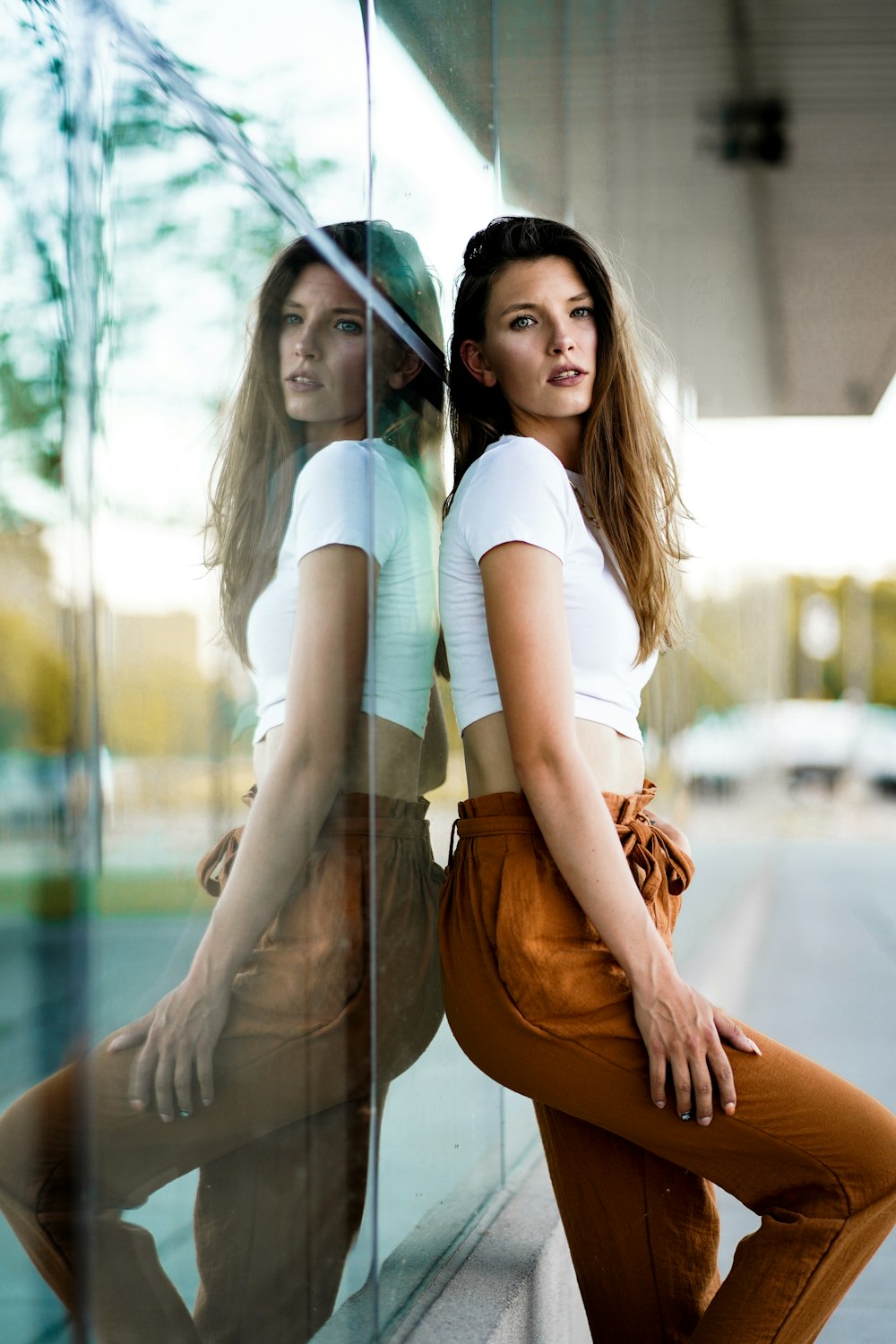 woman in white t-shirt and brown pants sitting on brown wooden bench