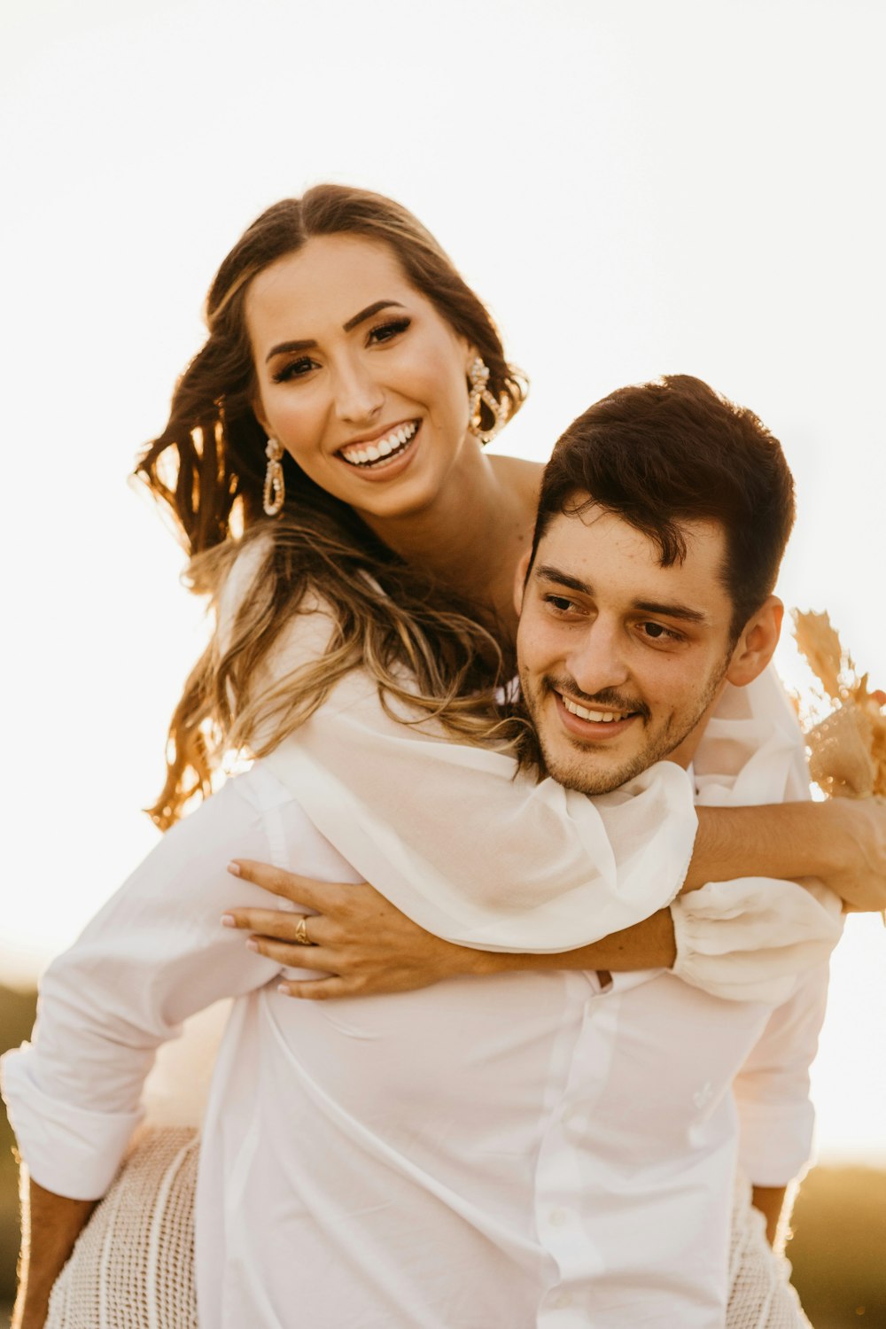 man in white dress shirt hugging woman in white dress