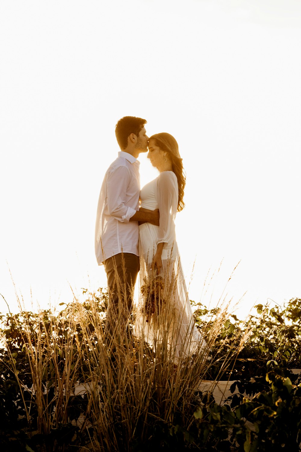 man and woman kissing on grass field during daytime