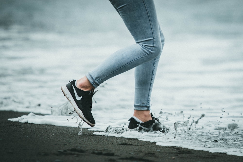 Person in blue denim jeans and black and white nike sneakers photo