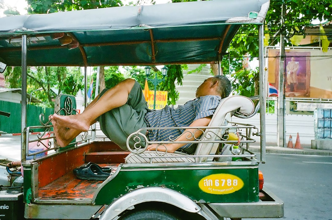 man in green and white stripe polo shirt driving green and white auto rickshaw during daytime